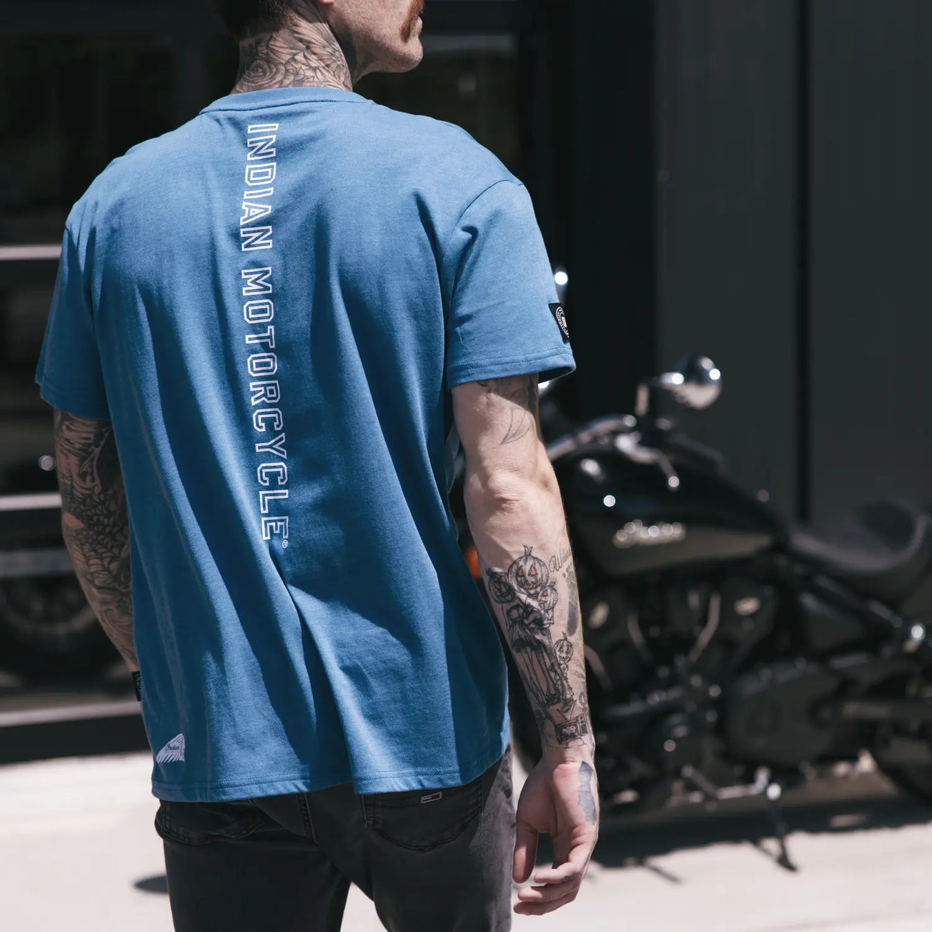 Man in a yellow shirt standing outside near a motorcycle